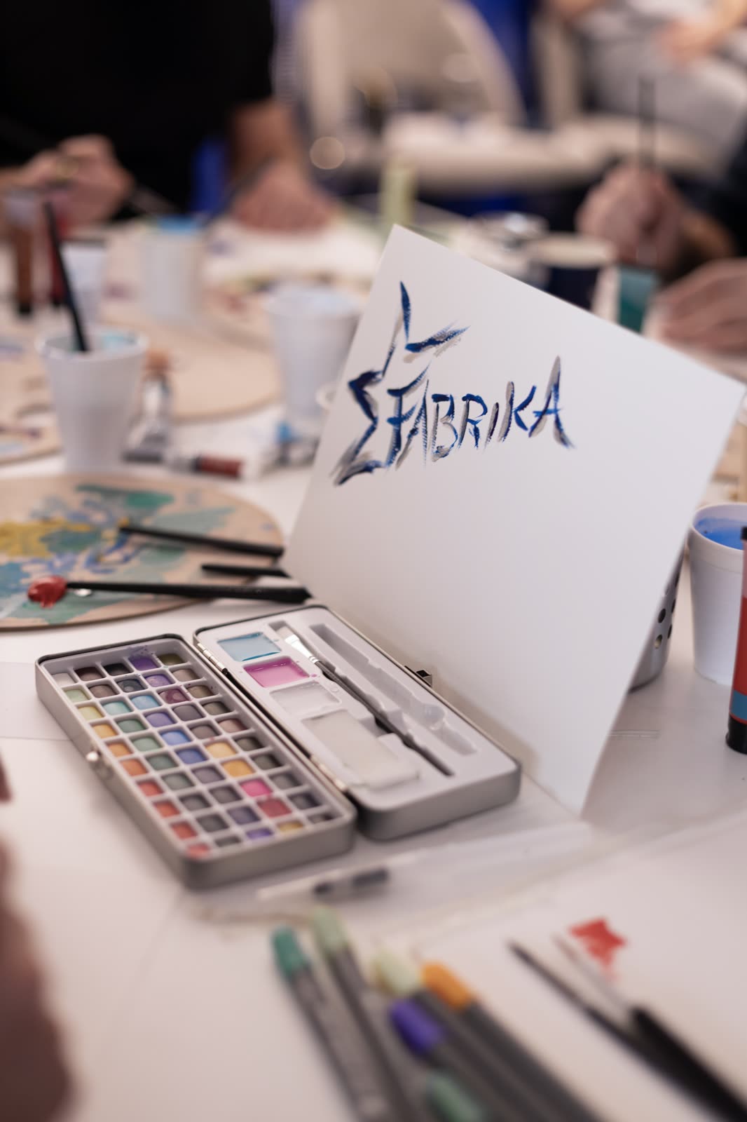 Art table with watercolours and the FABRIKA logo