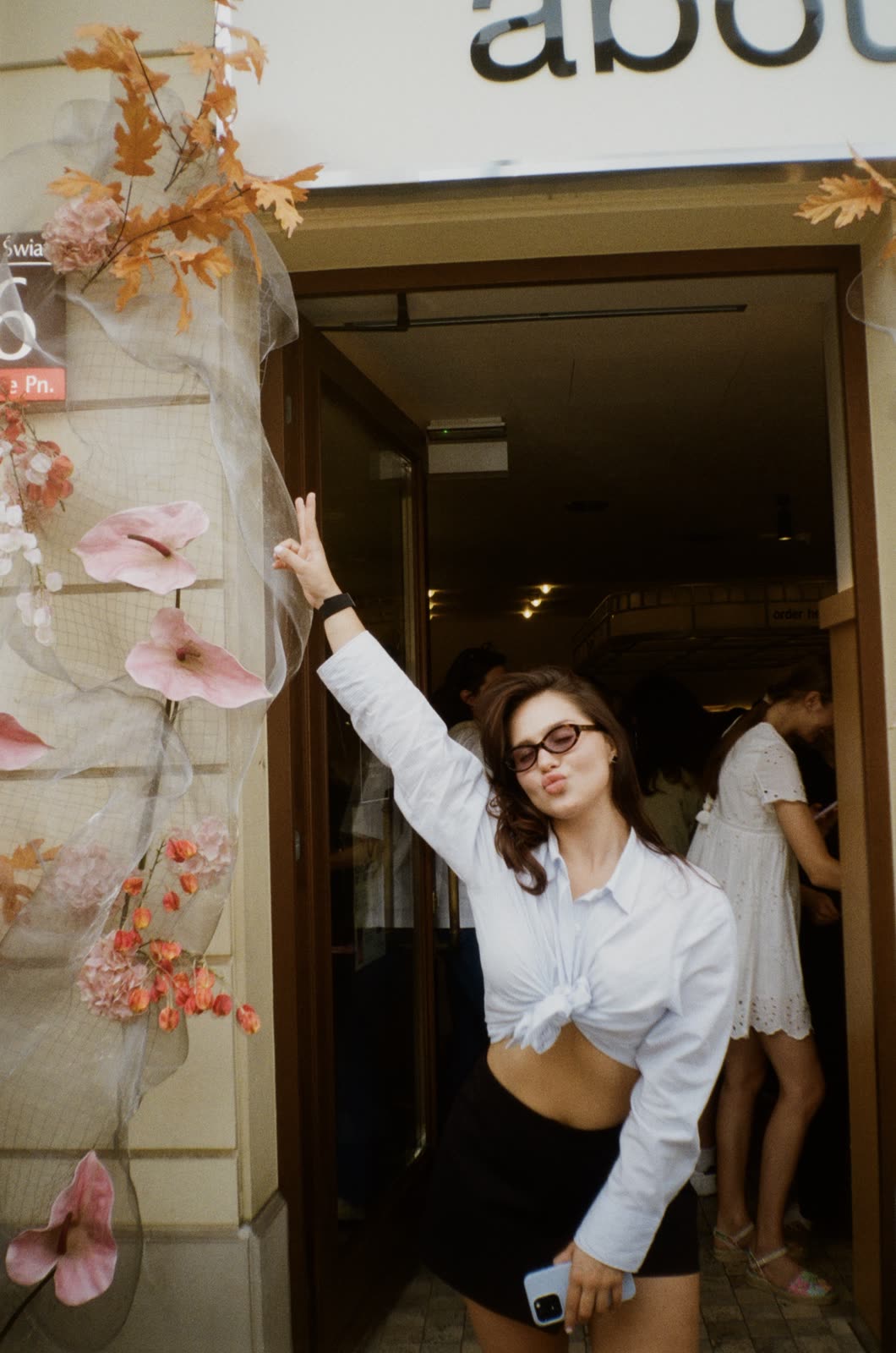 Guest waving from the flower arch at the About Matcha opening