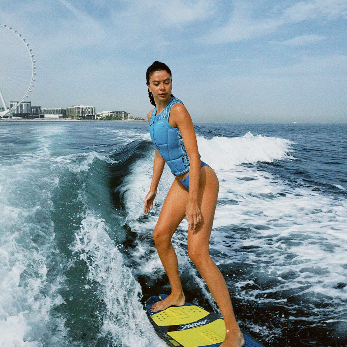 Wake-surfer riding a wave with the Dubai skyline behind