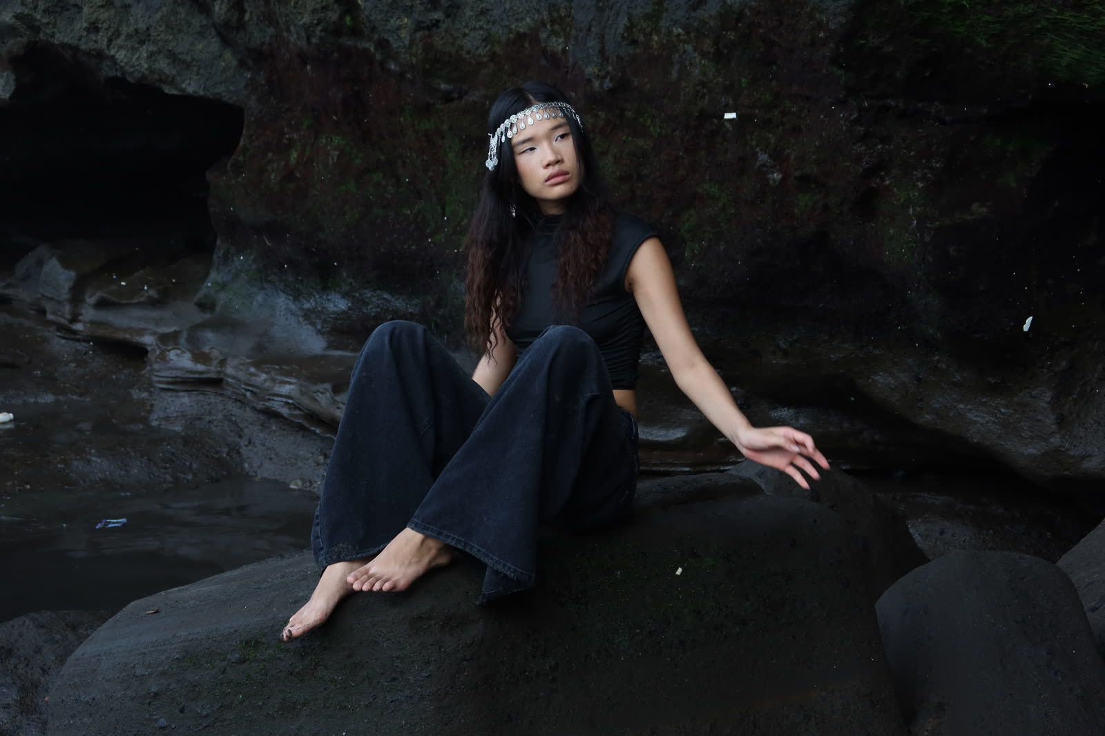 Model seated on dark rocks