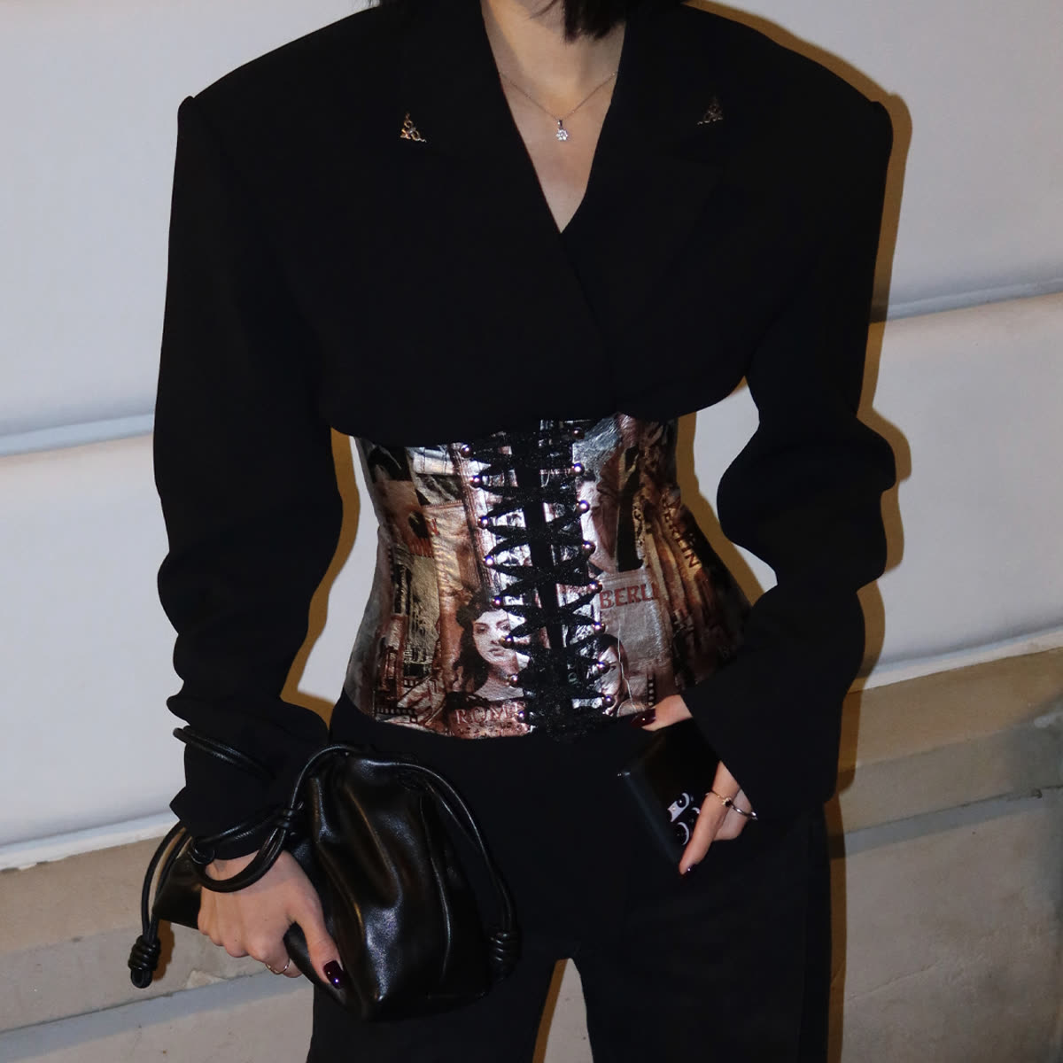 Model in a black suit and metallic corset, evening street
